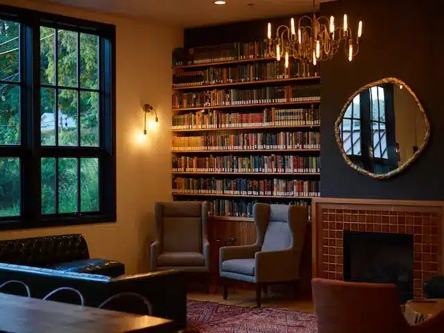 A large bookshelf in a corner by a window and a sitting area after creating a home library