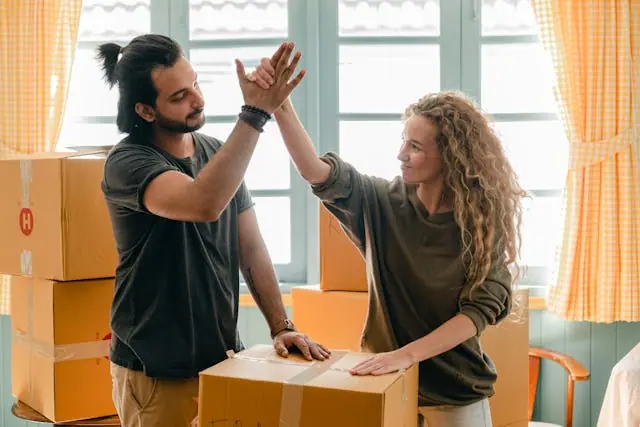 A couple high-fiving each other while packing boxes in their new home