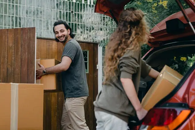 A man and a woman carrying boxes after relocation.