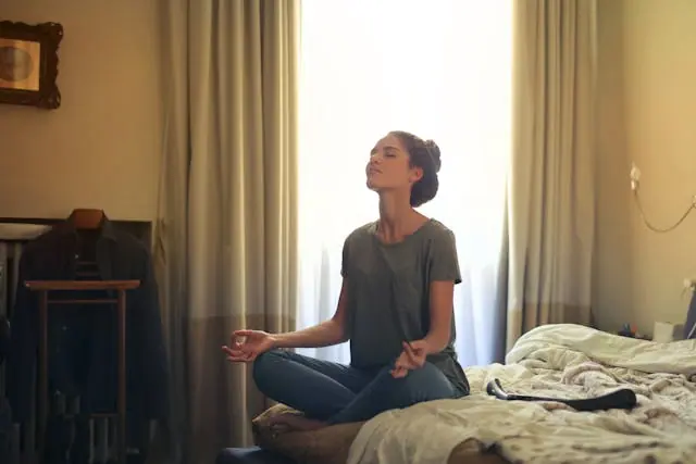 a woman meditating on her bed