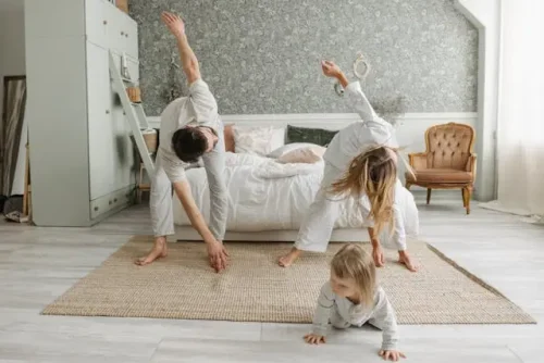 Family stretching together in a bedroom, creating morning movement routines as part of healthy habits.