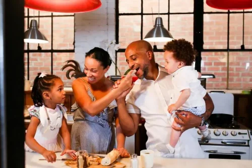 Family enjoying breakfast together in the kitchen, sharing laughter and food in a warm morning setting.