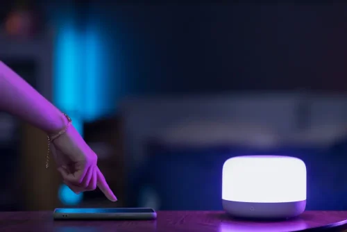 Smart lighting design setup with an adjustable color lamp and smartphone control, showing how lighting design can transform your mood at home.