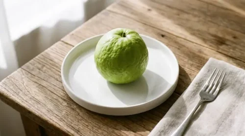 How much guava can diabetics eat? One medium-sized green guava resting alone on a white plate to demonstrate a safe serving.